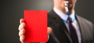 Businesman blows whistle and shows red card